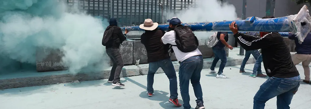 MEXICO-CITY-MEXICO-JUNE-03-Demonstrators-attempt-to-breach-the-gates-of-the-Mexico-s-Education-Ministry-building-as-riot-police-discharge-fire-extinguishers-at-them-during-a-protest-by-CNTE-teachers-in-Mexico-City-Mexico-on-June-03-2026-Members-of-National-Coordination-of-Education-Workers-CNTE-forced-their-way-into-Mexico-s-Education-Ministry-building-causing-damage-to-the-facilities-as-part-of-the-third-day-of-protests-following-the-declaration-of-a-national-strike